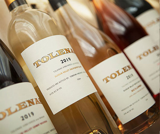 Tolenas wine bottles lined up horizontally