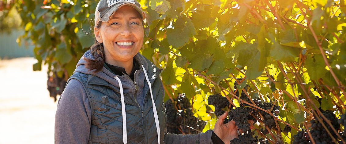 Lisa Howard holding grapes growing in a vineyard